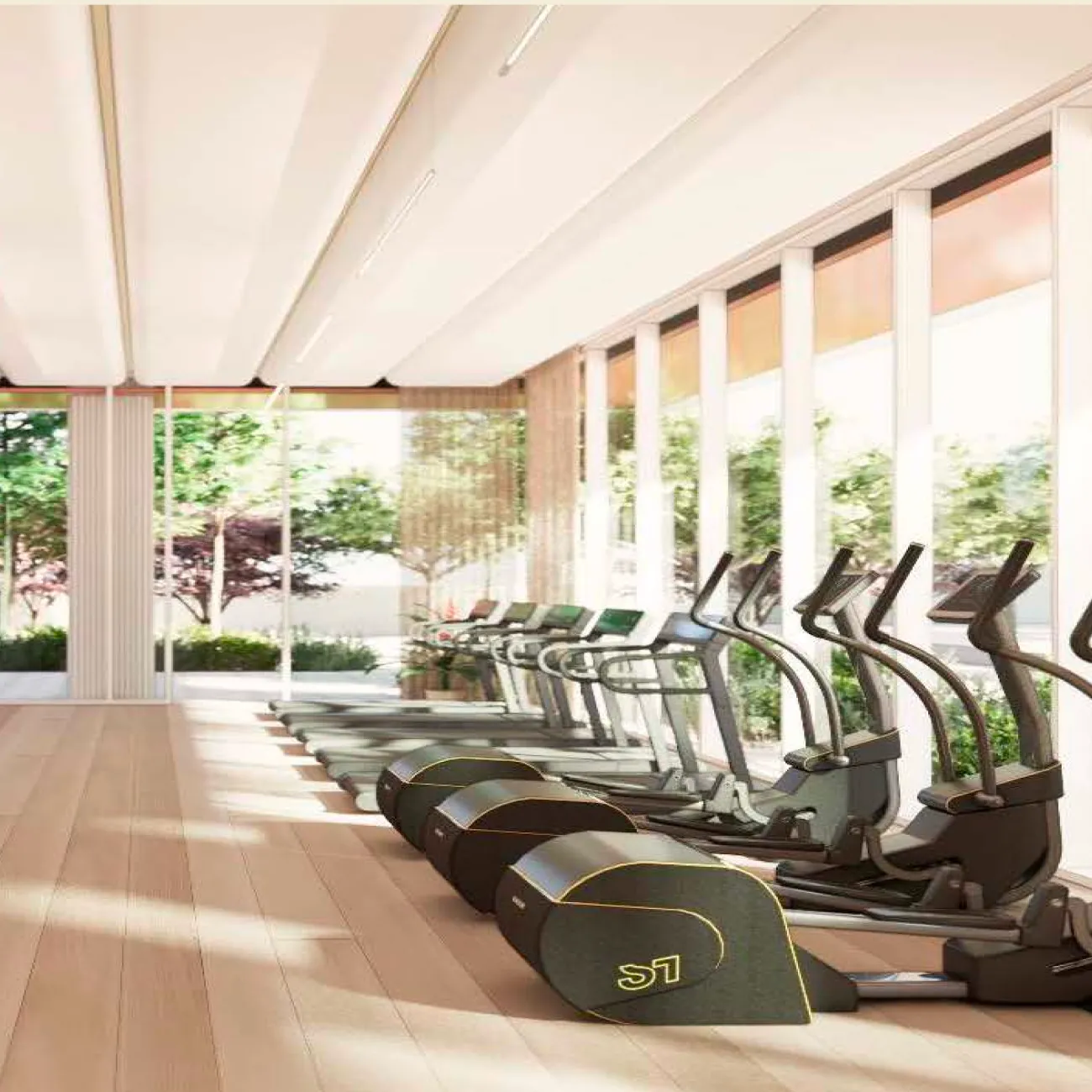 Bright fitness center with treadmills and ellipticals facing tall windows overlooking lush greenery